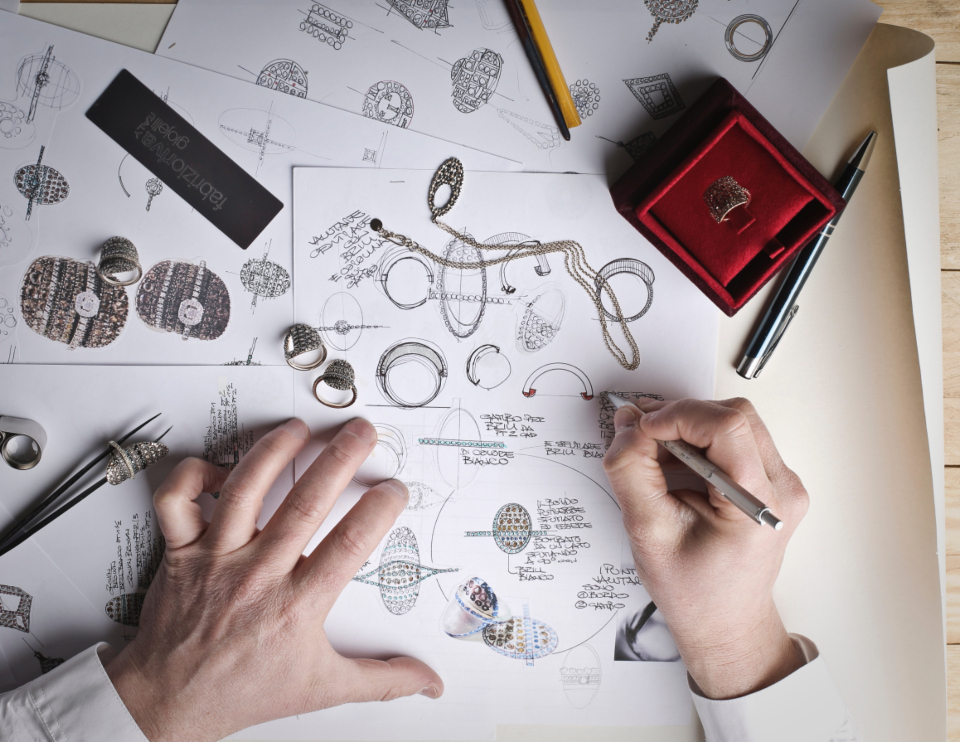 Hands sketching invention drawings at a desk